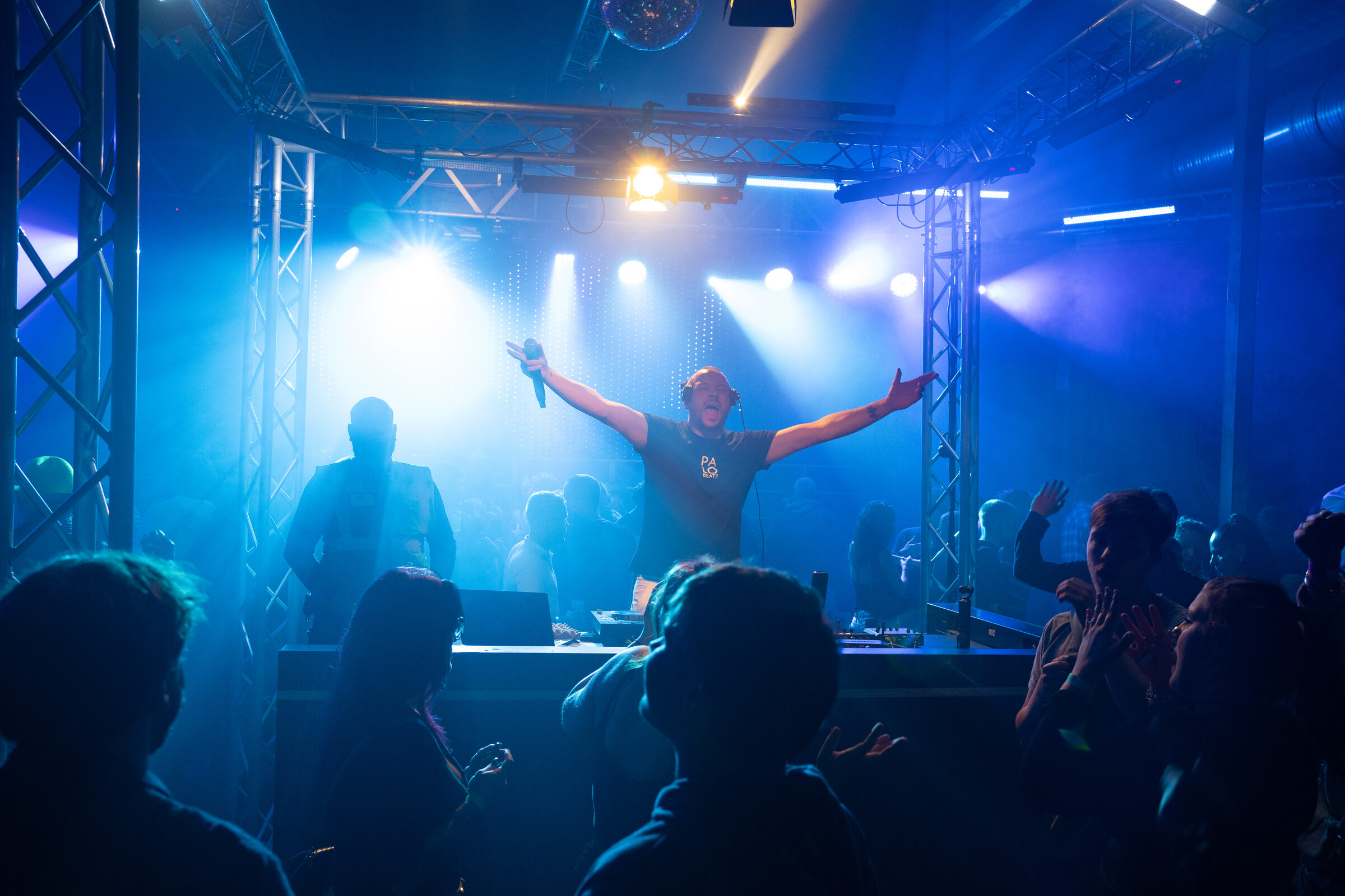 PALO BEATZ mit weit ausgebreiteten Armen auf der Bühne, blaues Licht